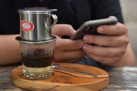 Close-up of a Vietnamese coffee and smartphone use, showing modern relaxation.
