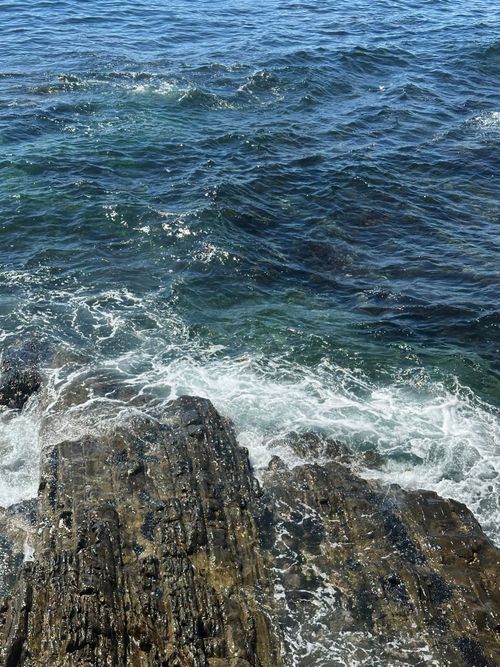 Free Waves crash on a rocky shoreline with vibrant blue ocean waters in Cape Town. Stock Photo