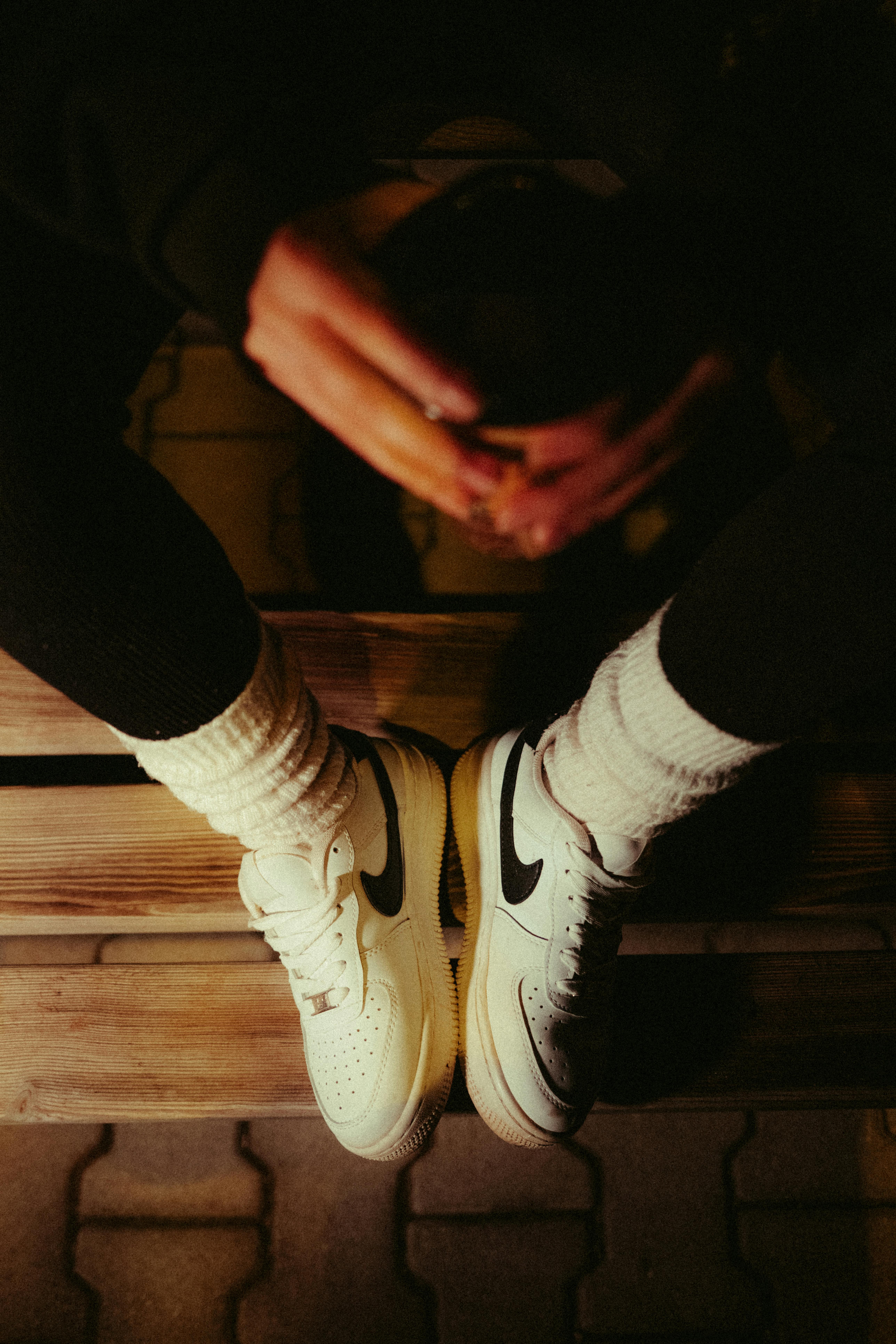 Kostenlos Draufsicht auf weiße Turnschuhe, die mit kuscheligen Socken getragen werden, in einer nächtlichen Straßenszene. Stock-Foto