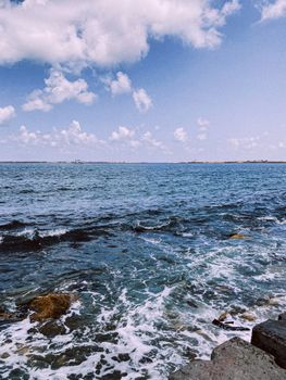 Scenic ocean view with waves crashing against rocks under a bright blue sky in Egypt.