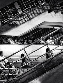 People on escalators in an urban setting, captured in striking black and white contrast.