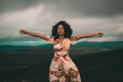 Mujer En Vestido Floral Blanco Y Rojo De Pie Sobre El Campo De Hierba Verde