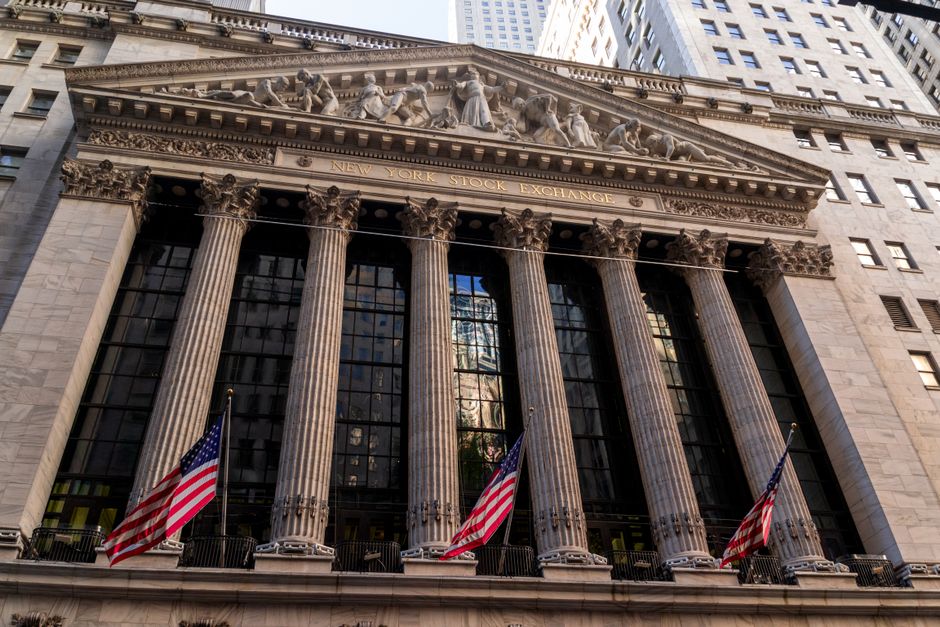 Iconic neoclassical facade of the New York Stock Exchange with American flags.