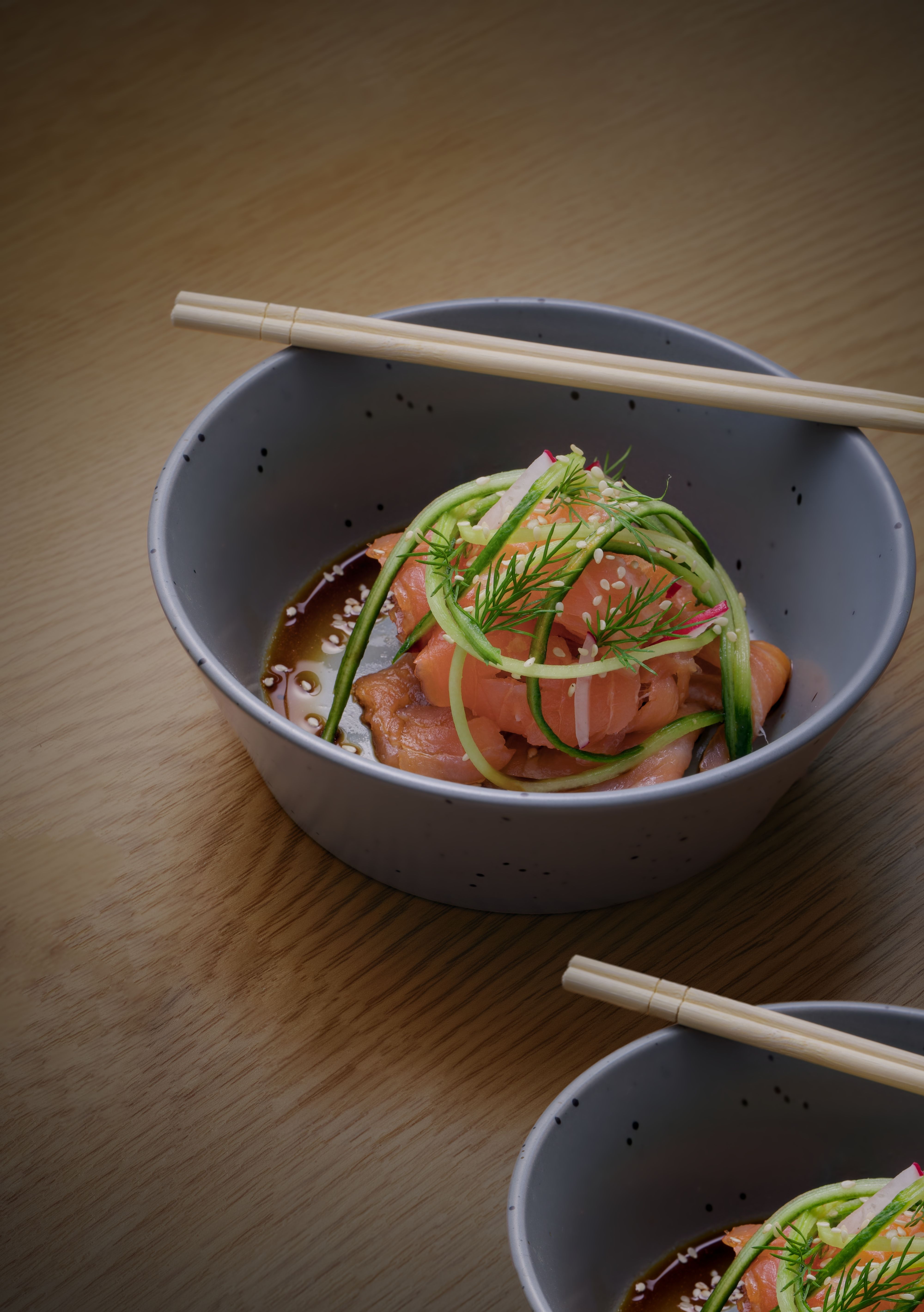 Appetizing salmon sashimi with vegetables in a bowl, perfect for Asian cuisine themes.