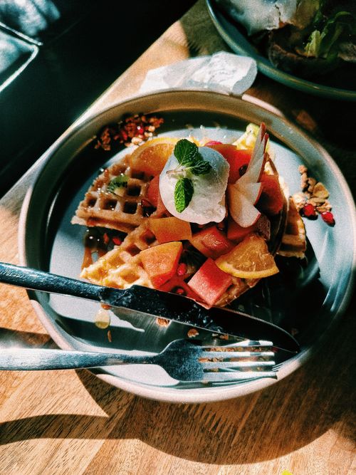 Free Mouthwatering waffles topped with fresh fruit and whipped cream in a cozy setting. Stock Photo