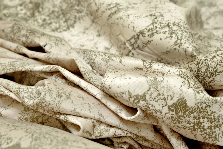 Detailed view of beige and green patterned fabric with organic textures.