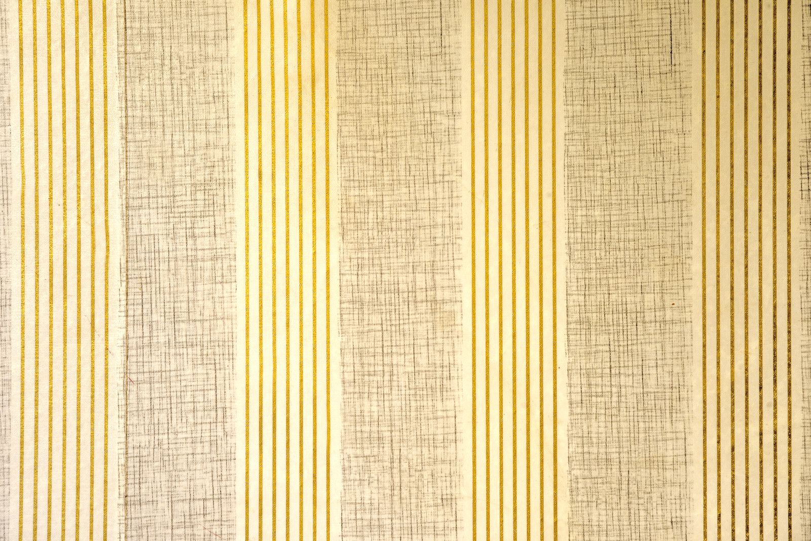 A textured wallpaper pattern with vertical beige and gold stripes on an interior wall