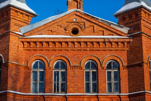 Free Vintage red brick building facade in winter with snow-covered roof and clear blue sky. Stock Photo