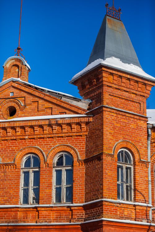 Free Historic red brick building with tower against a vibrant blue sky, showcasing classic architecture. Stock Photo