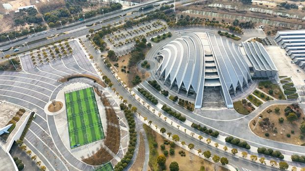 Aerial view of futuristic architectural complex with soccer field and parking lot.