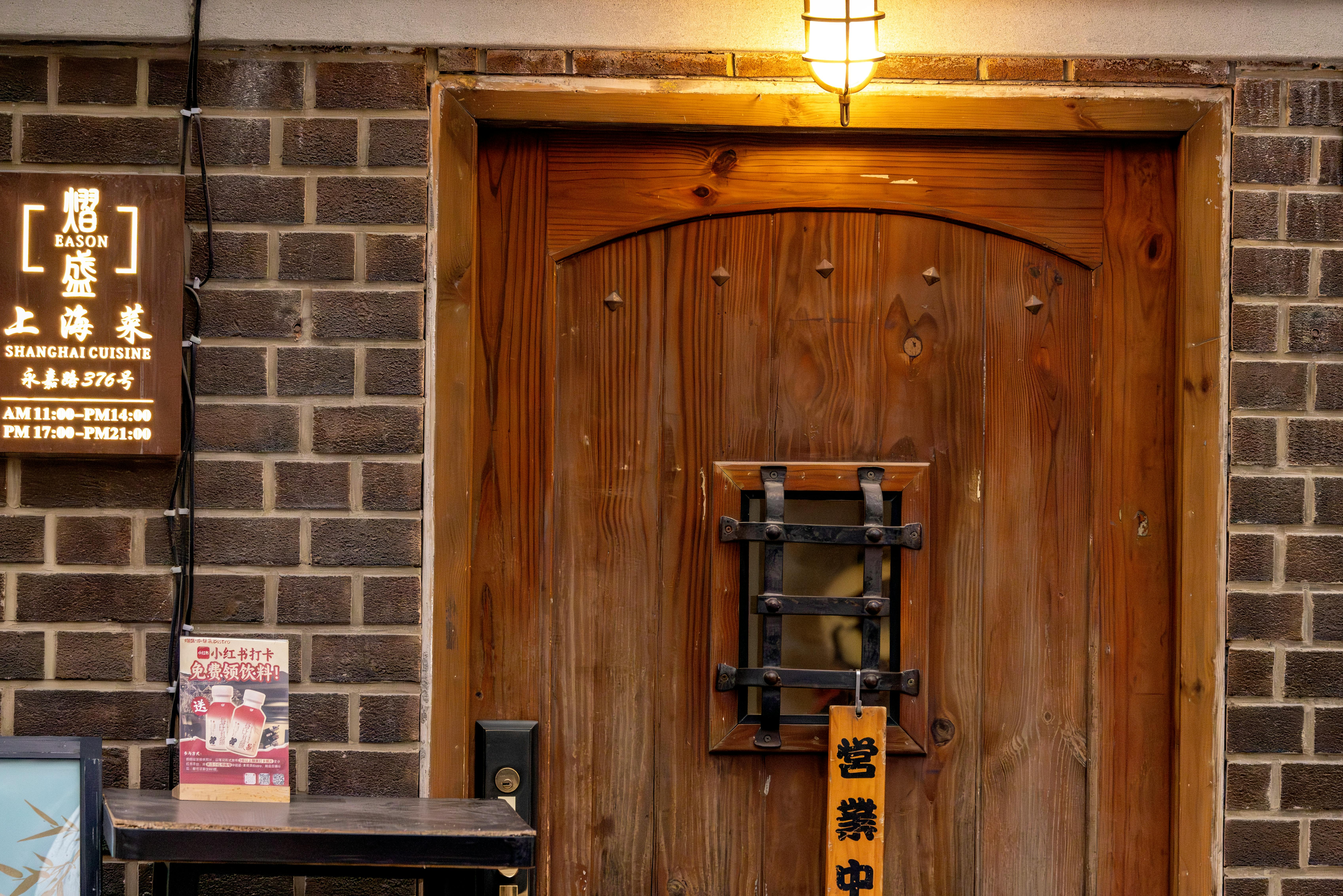 Warmly lit wooden door entrance of a Shanghai cuisine restaurant with vintage signage