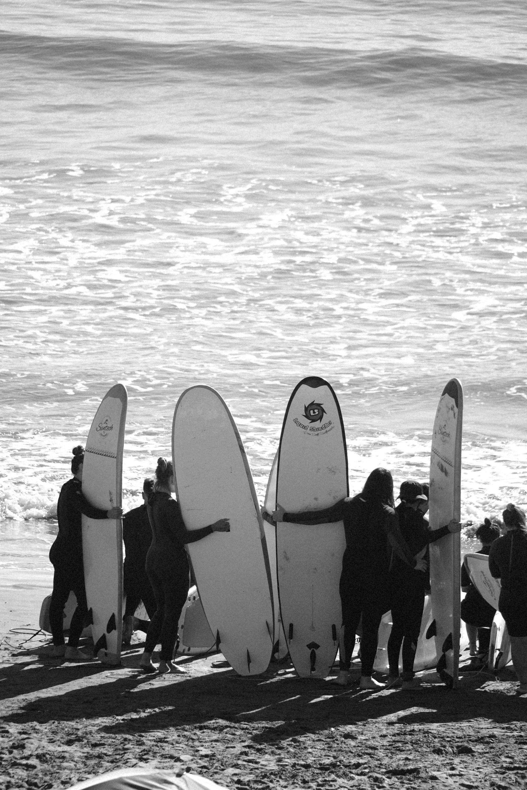 A group of surfers carrying boards beside the sea