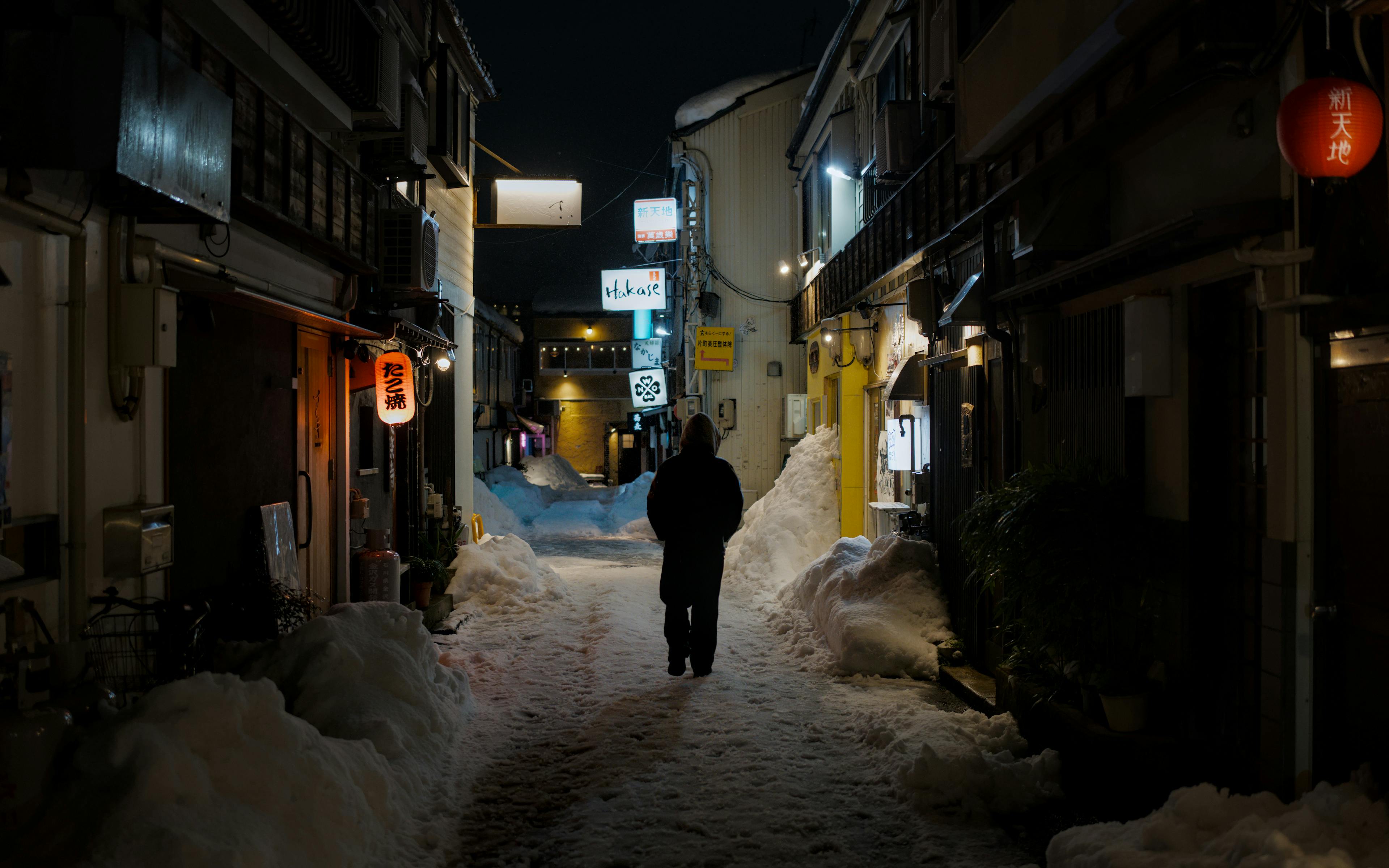 Gratis Una figura solitaria cammina di notte in un vicolo innevato a Kanazawa, in Giappone. Foto a disposizione