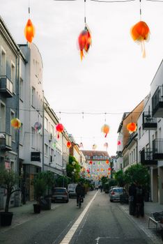 Colorful lanterns hang over a lively street, creating a festive atmosphere in the city.