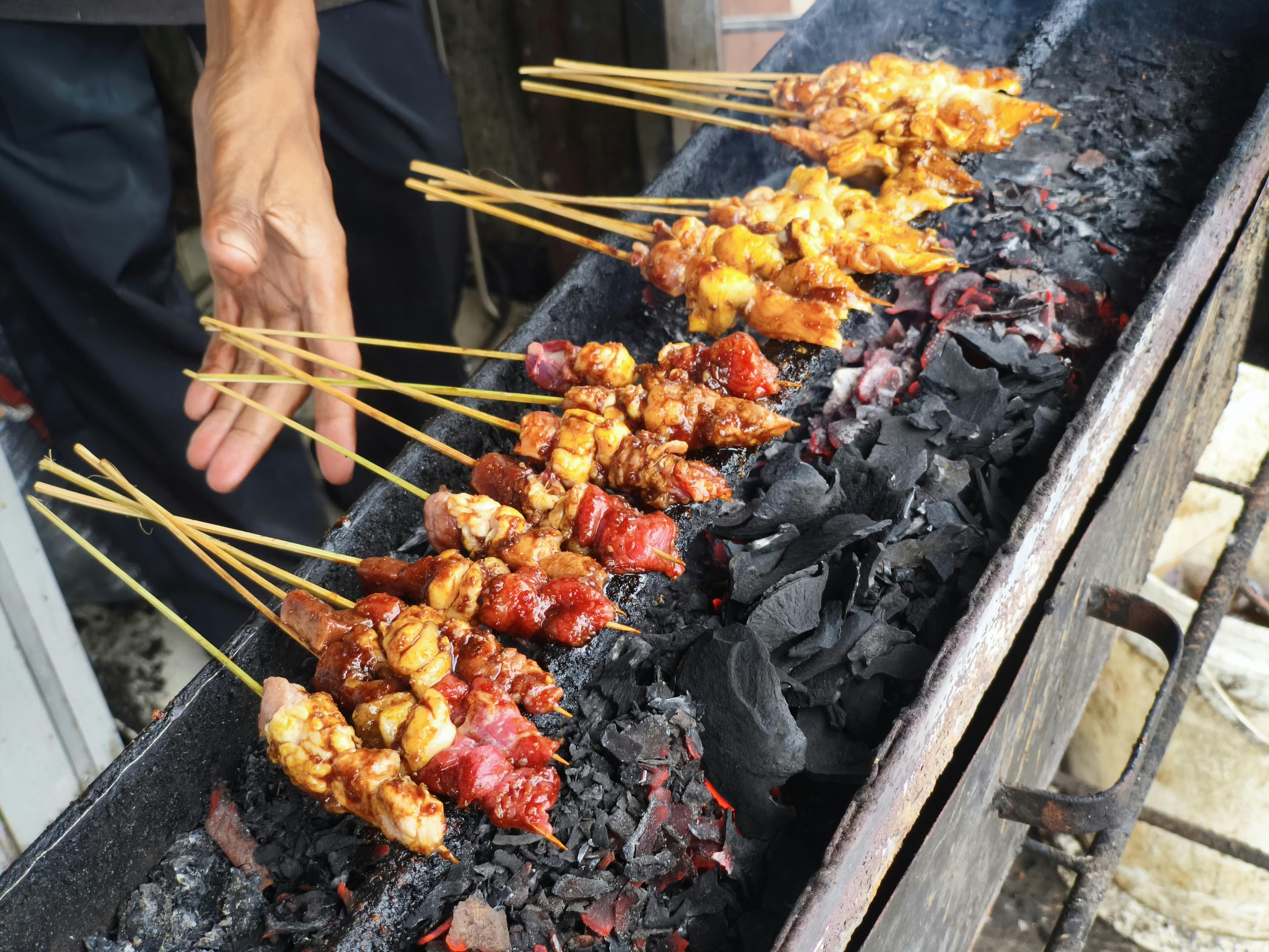 Rows of chicken and beef satay skewers grilling over charcoal at Satay Street outside Lau Pa Sat Singapore