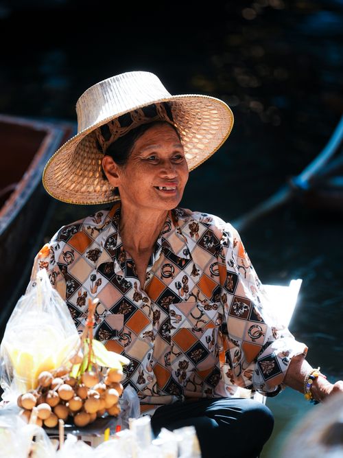 Free Asian woman in a hat selling fresh fruits at a vibrant floating market during the day. Stock Photo