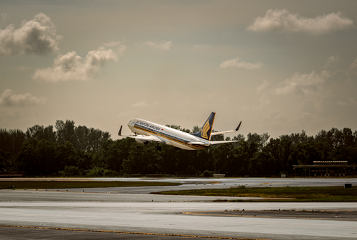 An airplane takes off from an airport runway, soaring into a partly cloudy sky.