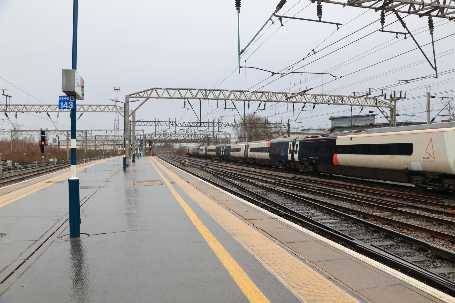 A high-speed train at a wet station platform in the UK during a rainy day, showcasing modern transport.
