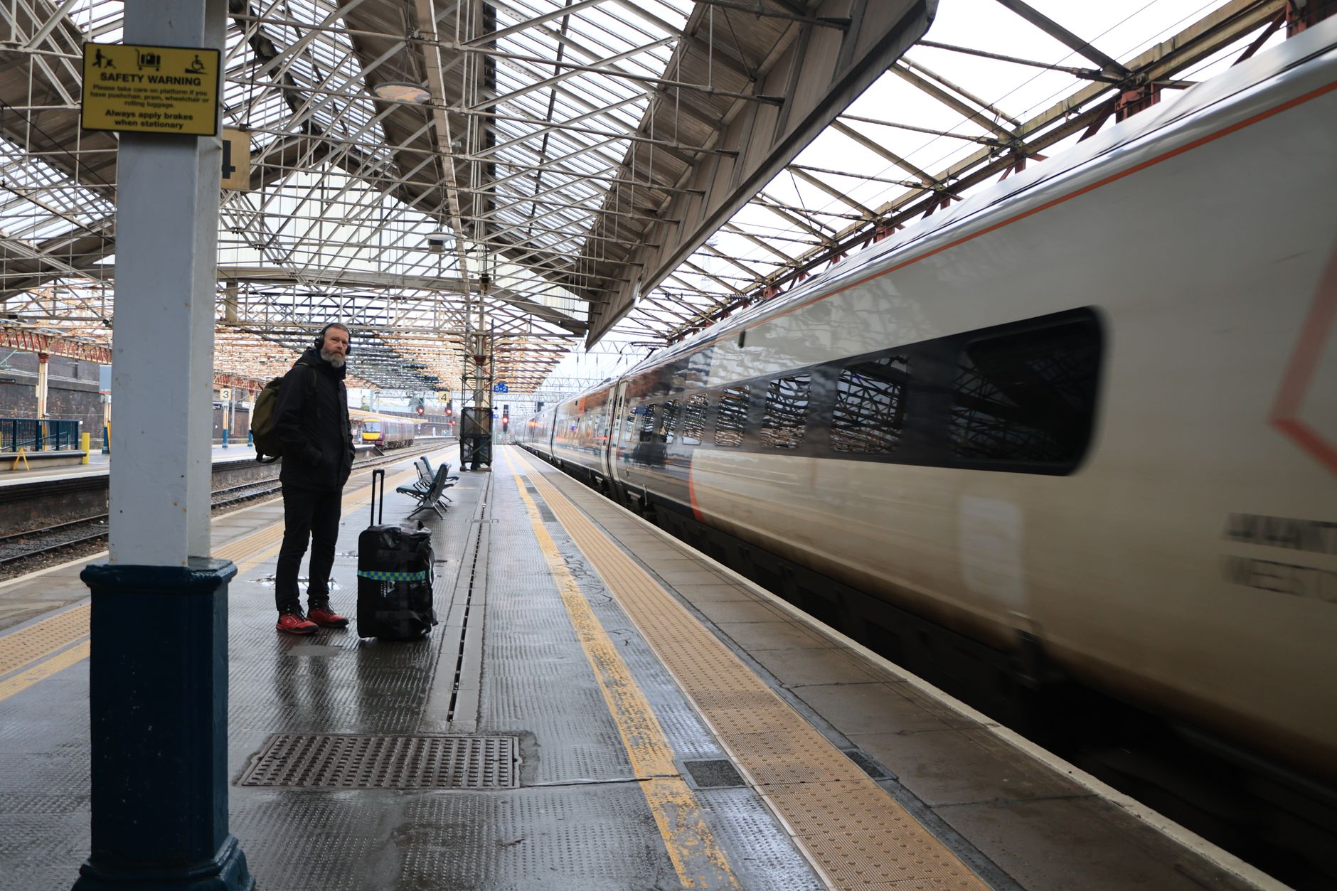 Traveler waiting near platforms after using station lockers at a European rail hub