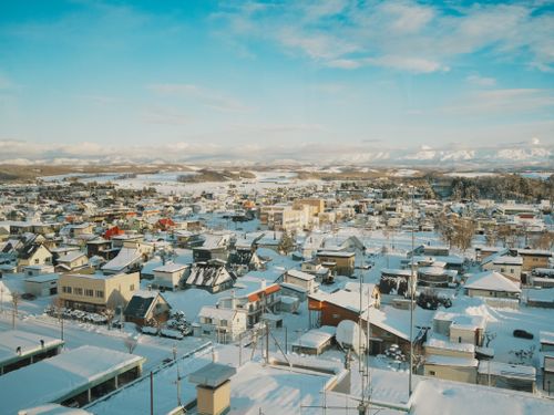 Free Scenic aerial view of a snow-covered town in Hokkaido, Japan during winter. Stock Photo