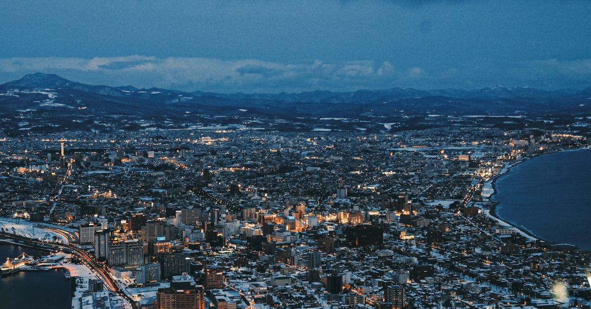 Stunning aerial view of Hakodate at night, showcasing a winter landscape and illuminated city lights.