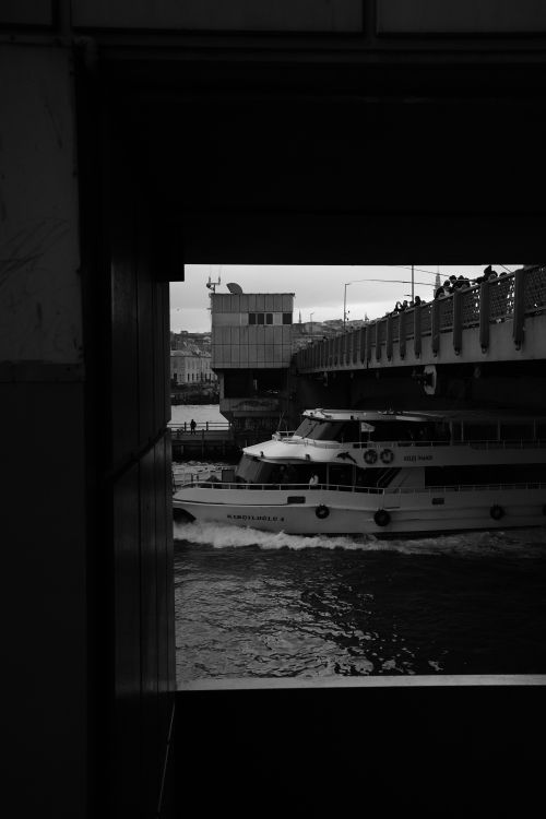 Free Black and white photo capturing a ferry under a bridge in Istanbul, framed by shadows. Stock Photo