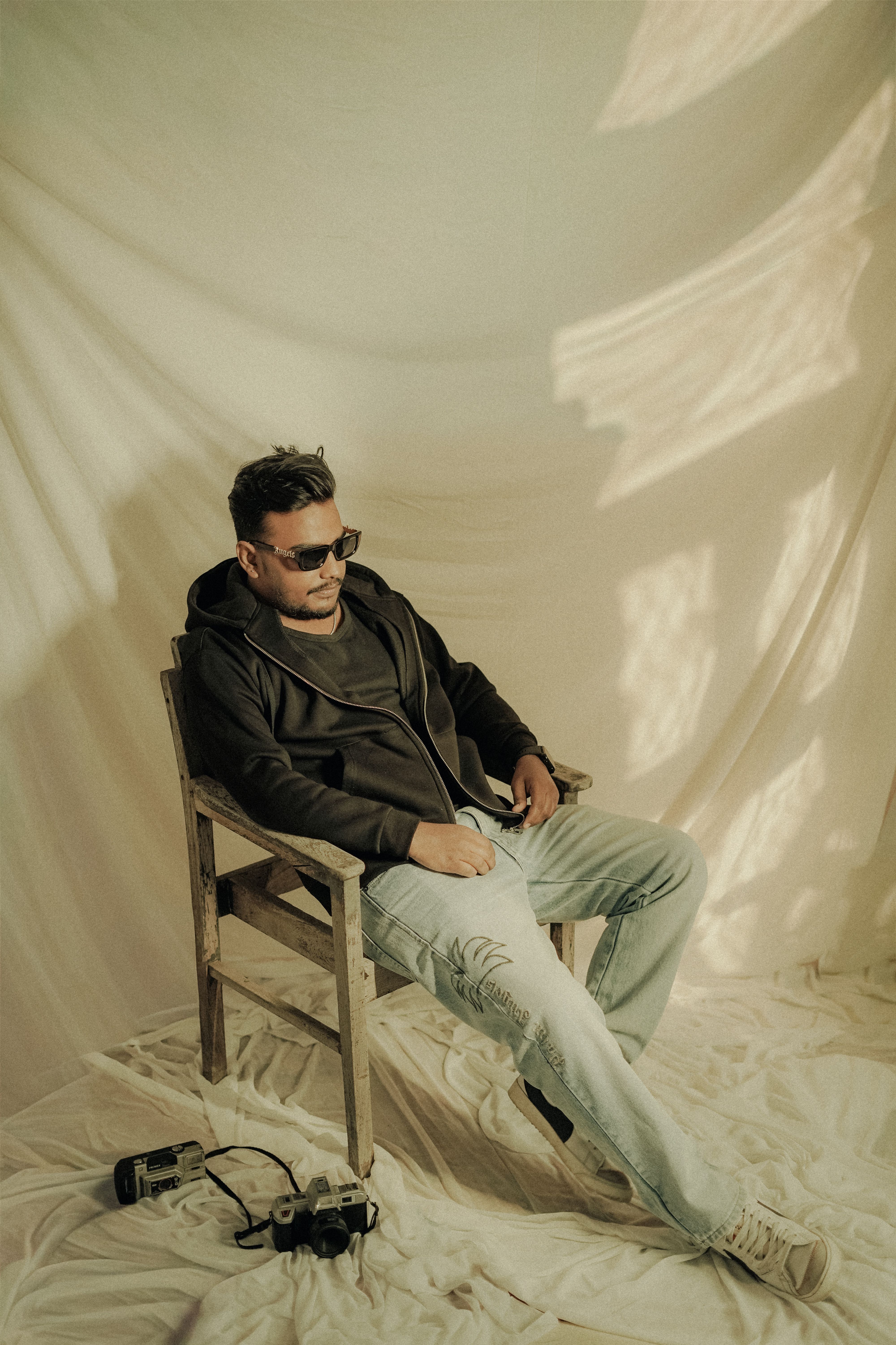 A man in sunglasses poses in a vintage setting, exuding style and attitude.