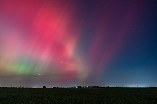 Vibrant Northern Lights display with vivid colors in the night sky above a calm landscape.