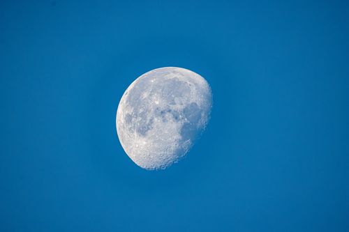 Free Detailed view of the moon's surface against a clear blue sky during daytime. Stock Photo