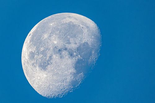 Free Detailed image of the moon in daylight with visible craters and texture, set against a clear blue sky. Stock Photo