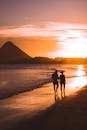 一对情侣的剪影在壮丽的日落时分漫步于海滩，捕捉到了宁静与浪漫