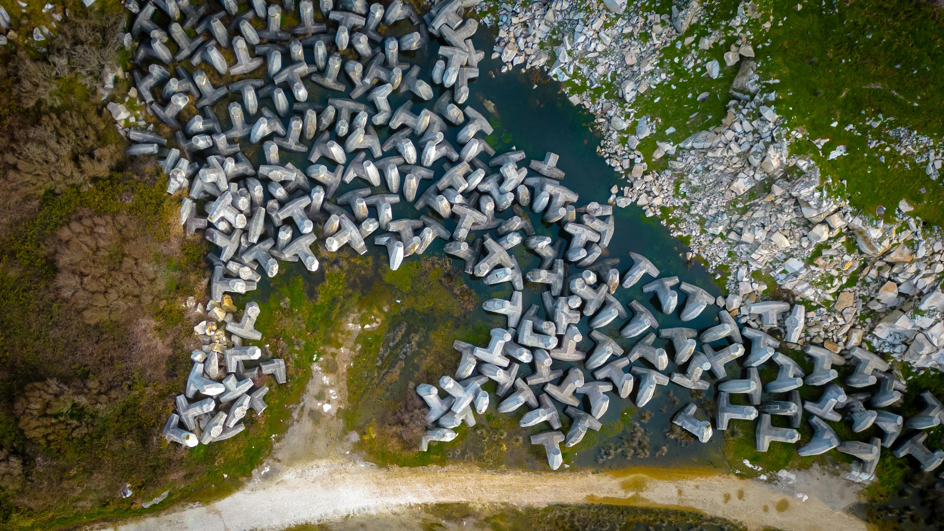 Captivating aerial photo of dolos formations along the coast in Lugo, Spain, with vibrant greenery.