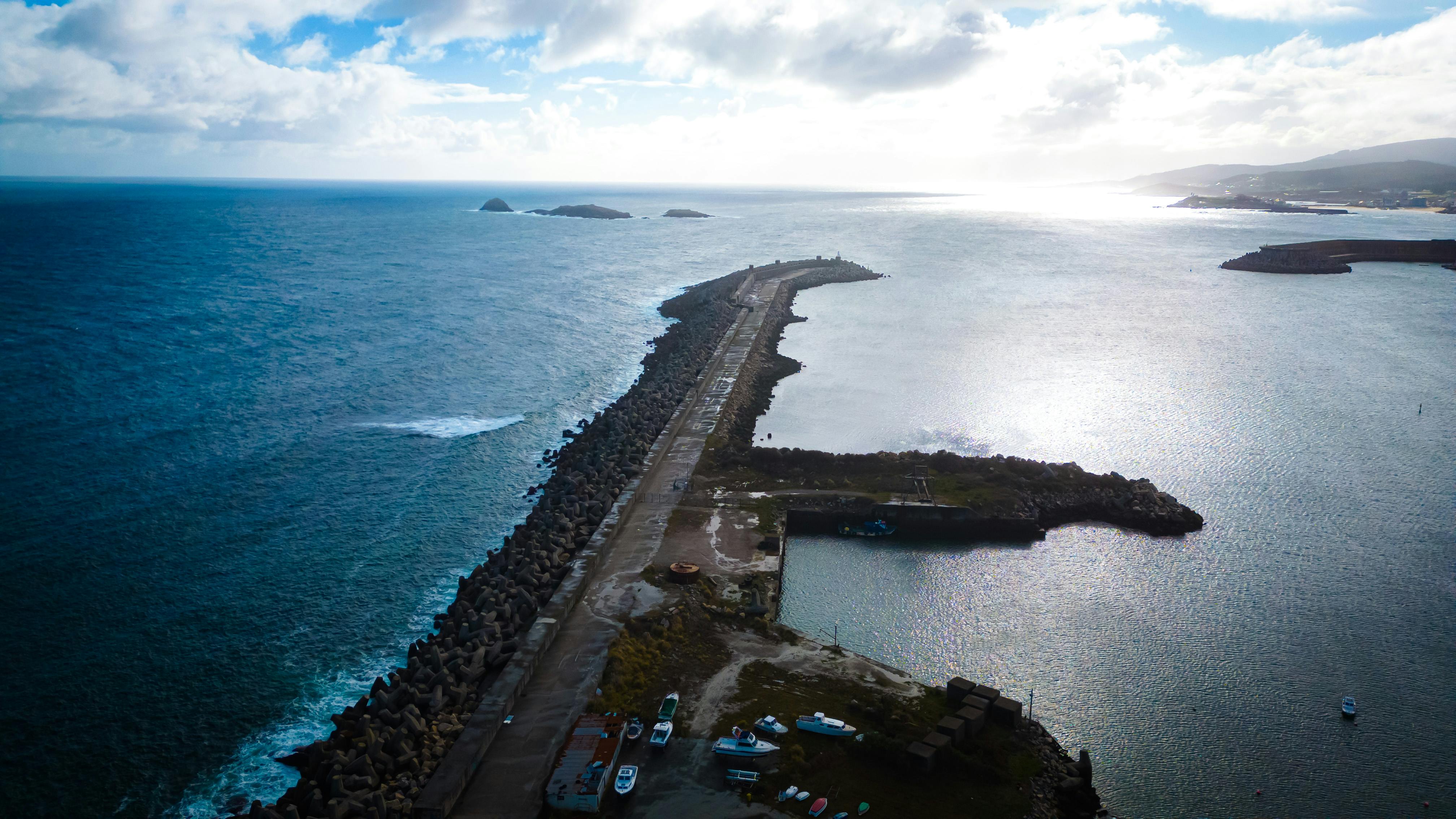 Stunning aerial view of a coastline and breakwater in Lugo, Spain, capturing the expansive sea and sky.