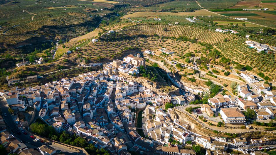 Stunning aerial view of Setenil de las Bodegas with white houses and olive groves.