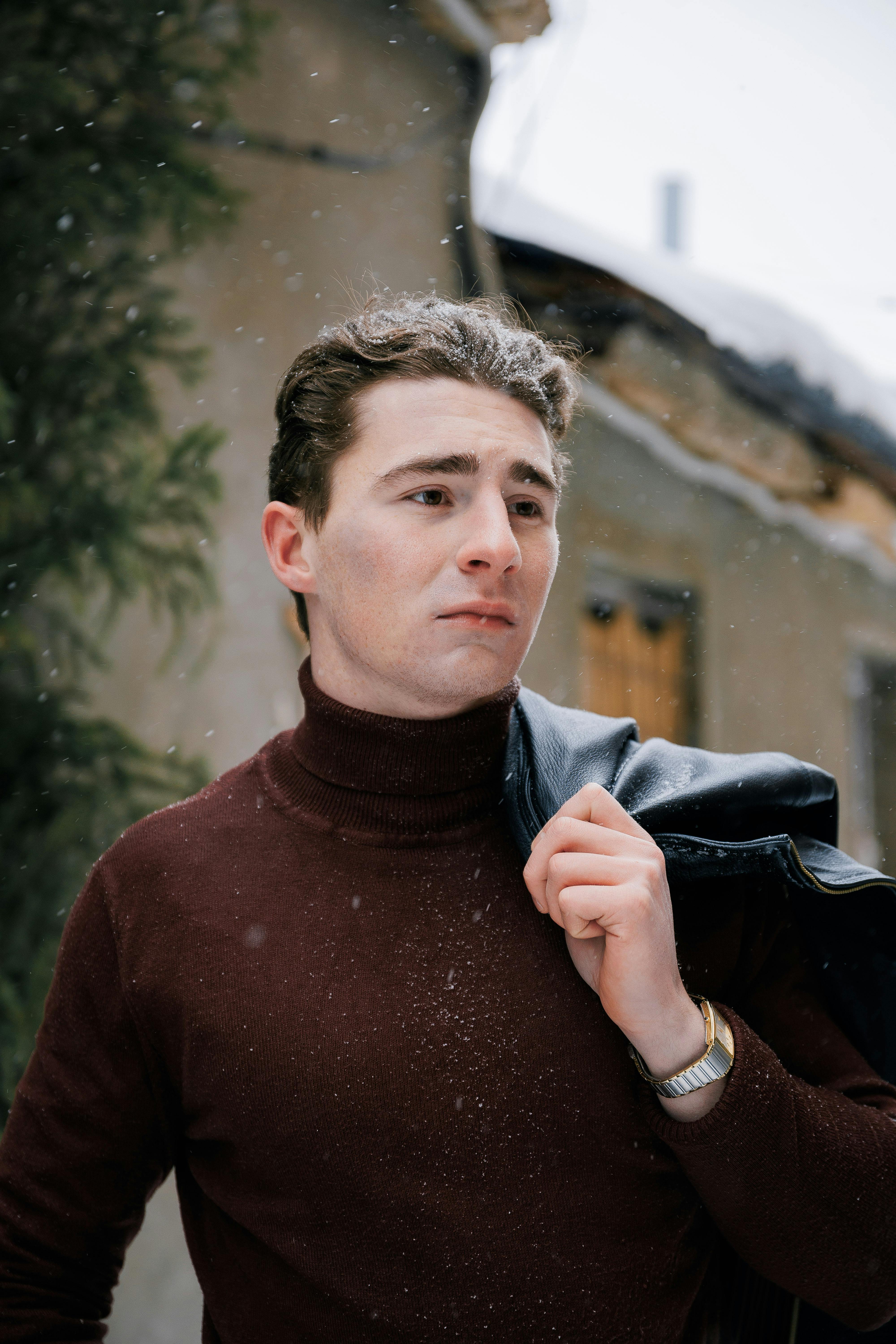 grátis Retrato de um jovem caminhando ao ar livre no inverno, com flocos de neve caindo. Foto profissional