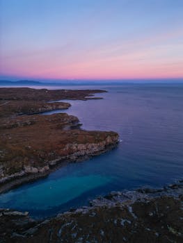 A breathtaking aerial view of the Torridon coastline at twilight with vibrant pink and purple skies.