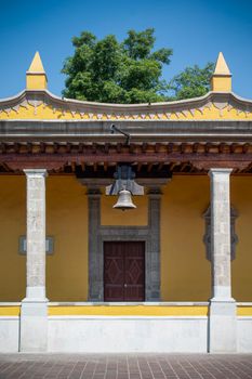 Charming yellow house with bell in Coyoacán, showcasing colonial architecture in vibrant Ciudad de México.
