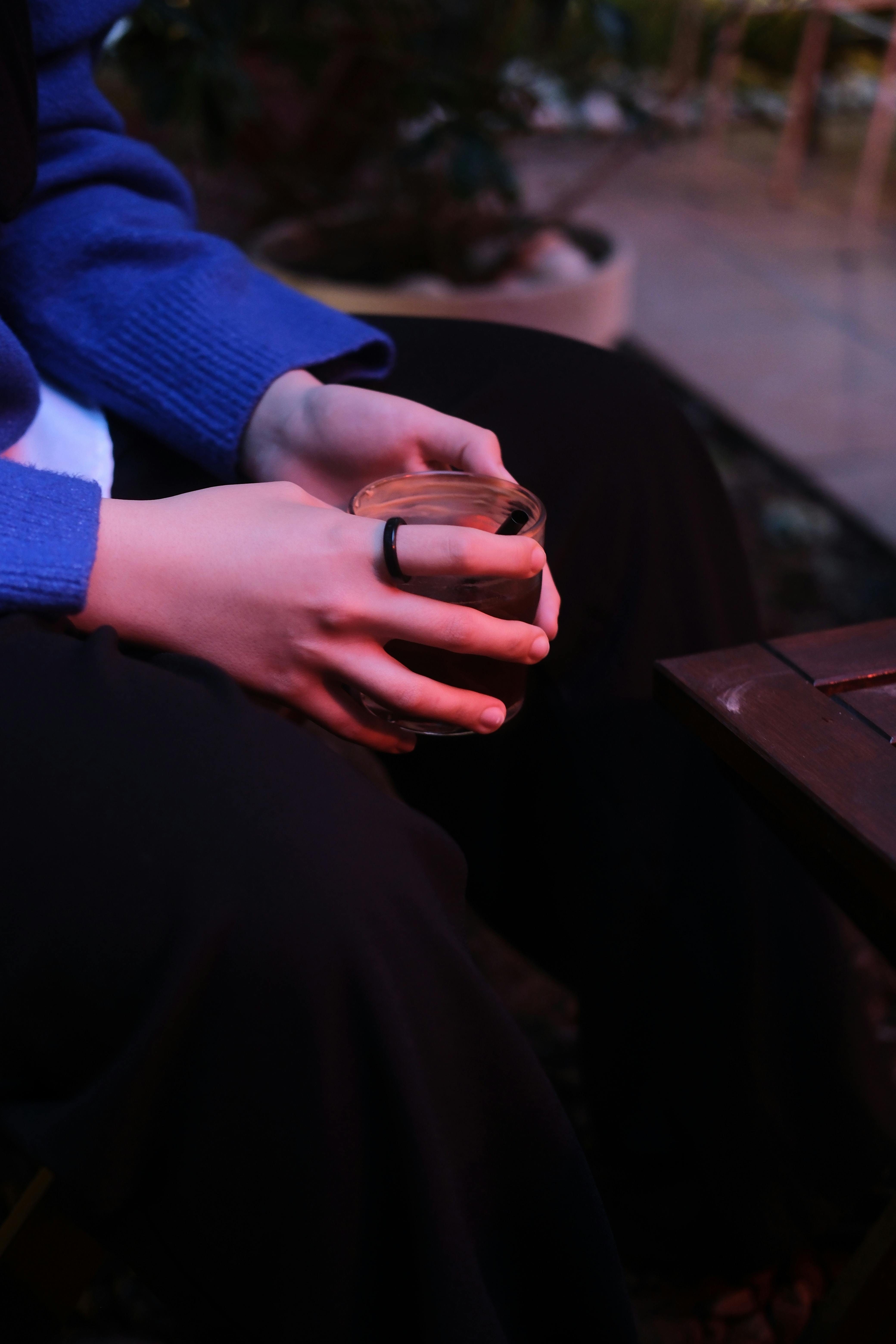 Free Close-up of hands holding a coffee cup in an outdoor evening setting, creating a cozy mood. Stock Photo