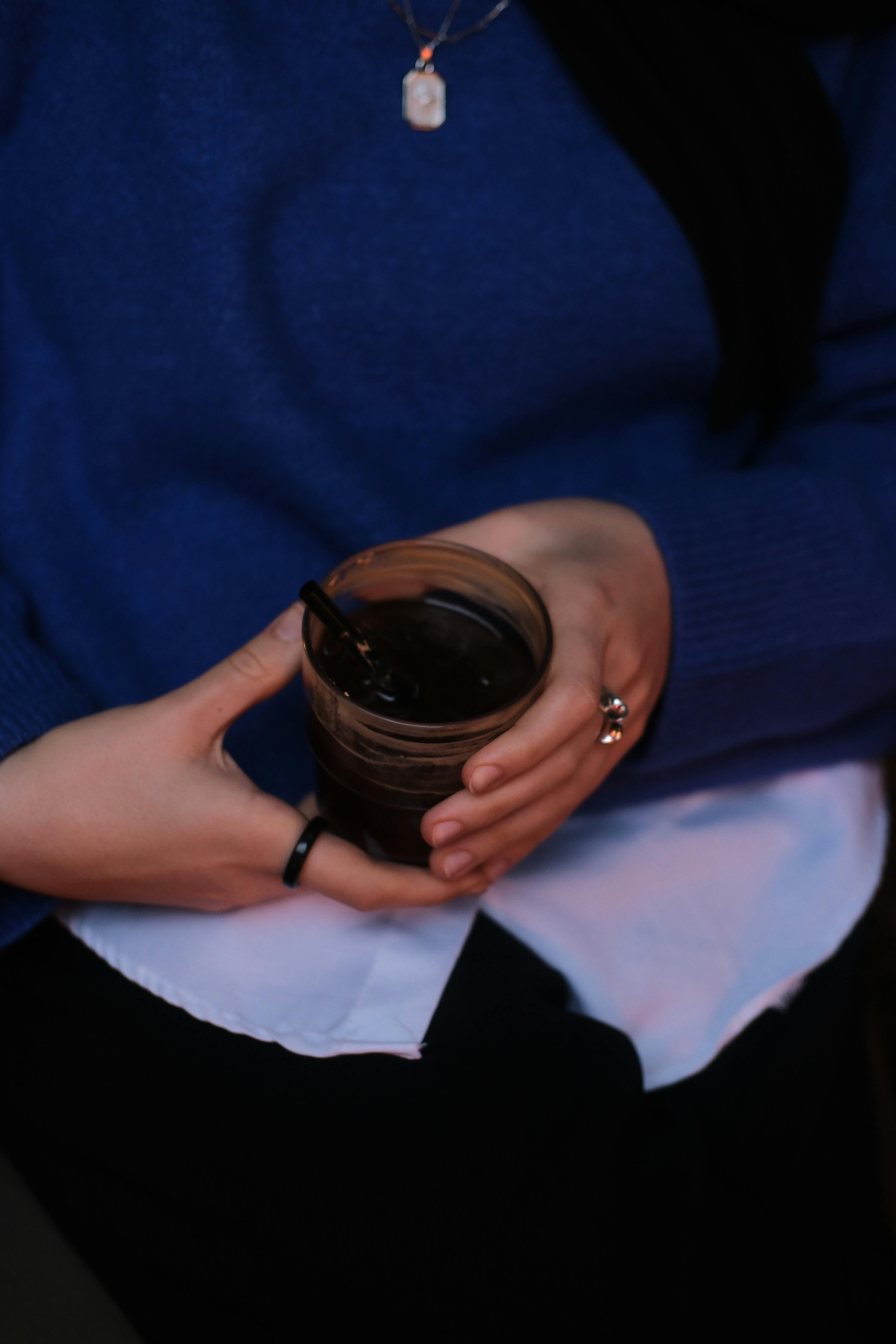 Free A woman in blue holding a glass of coffee with elegant jewelry. Stock Photo