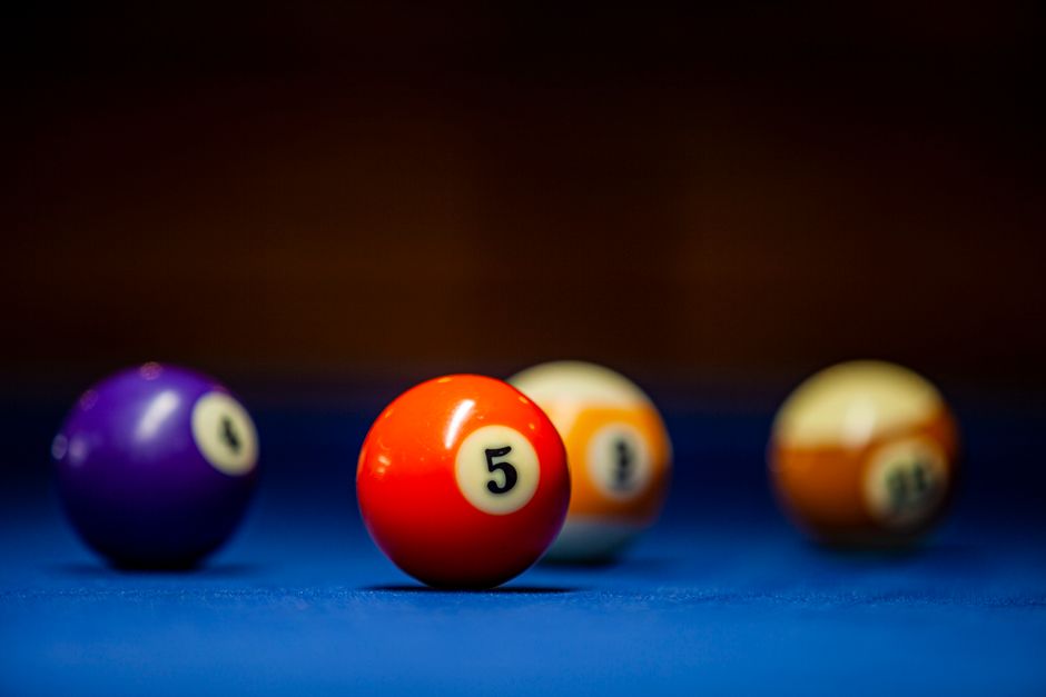 Colorful pool balls on a billiard table focus on the number five.