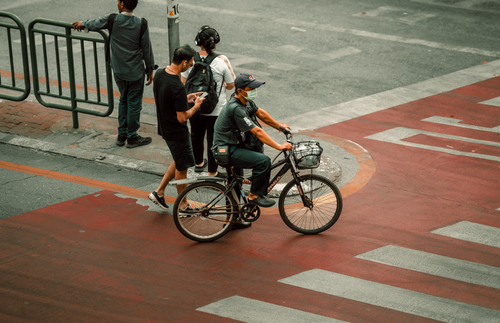 Free Busy Bangkok street intersection featuring a cyclist and pedestrians, captured on a warm day. Stock Photo