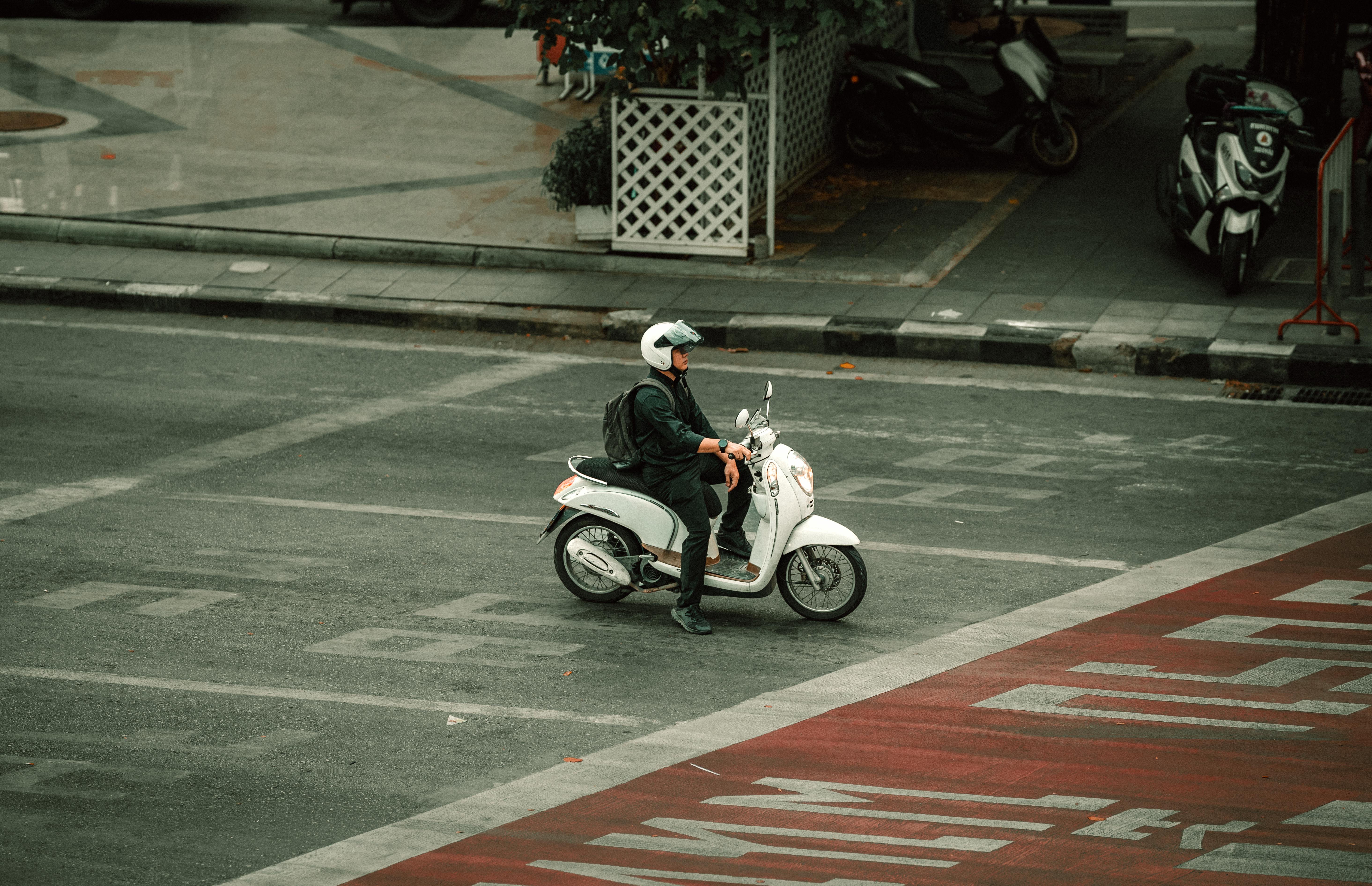 Miễn phí Một người lái xe máy đang chờ ở một ngã tư đường tại Bangkok, Thái Lan dưới bầu trời trong xanh, thể hiện cuộc sống đô thị. Ảnh lưu trữ