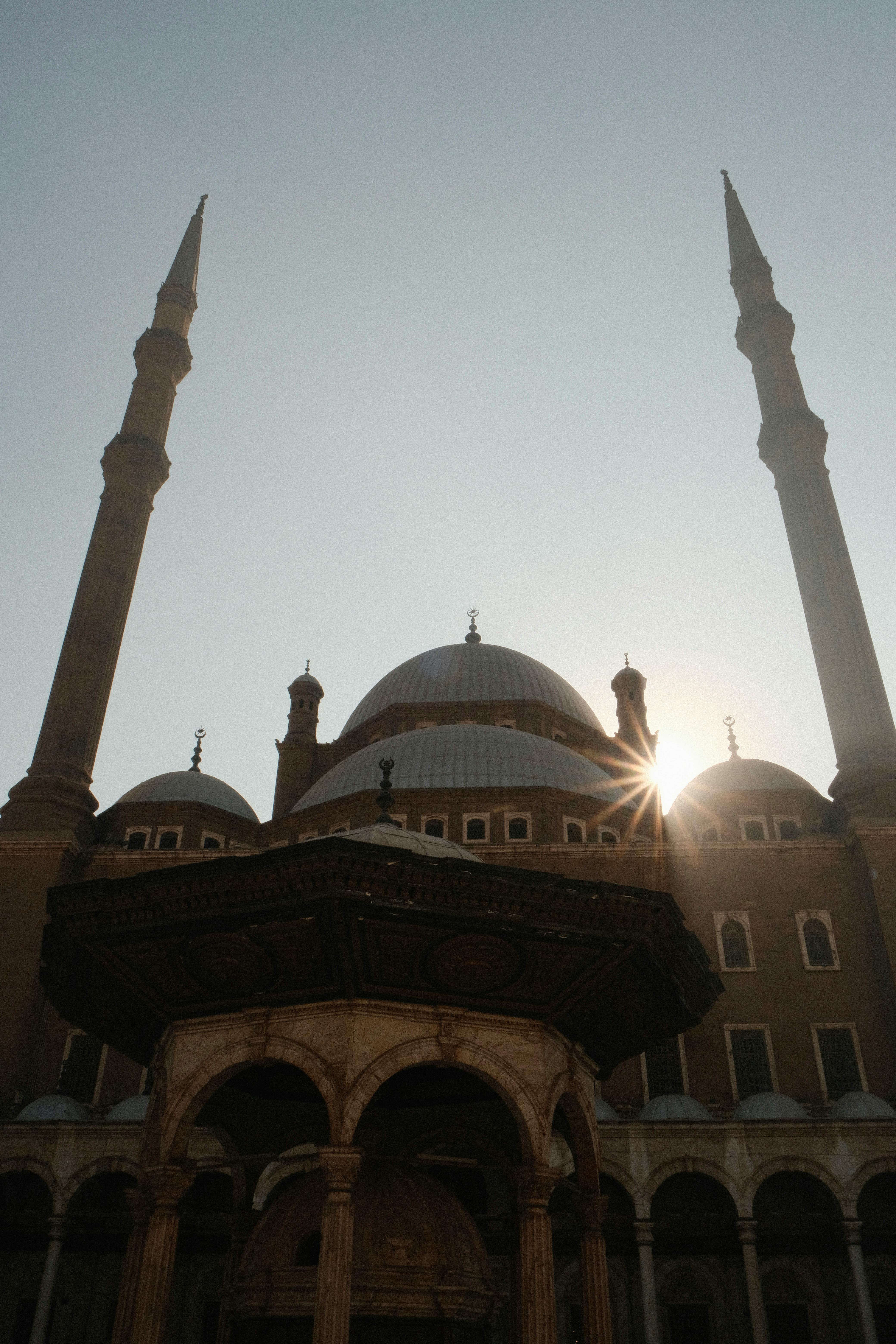 Stunning sunrise view of the iconic Muhammad Ali Mosque in Cairo, Egypt with sunburst effect.