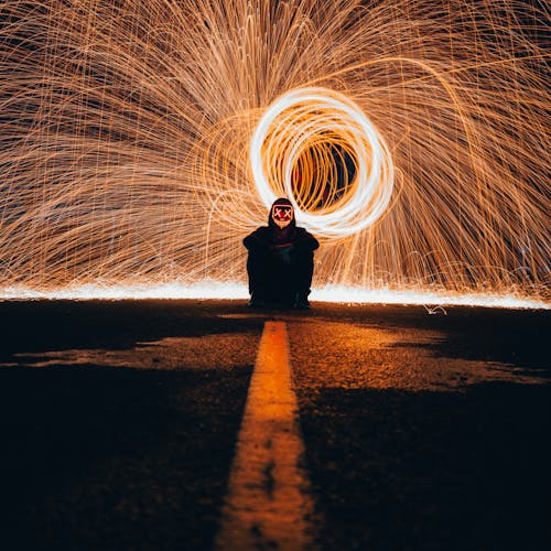 Person Sitting on Brown Sand With Lights