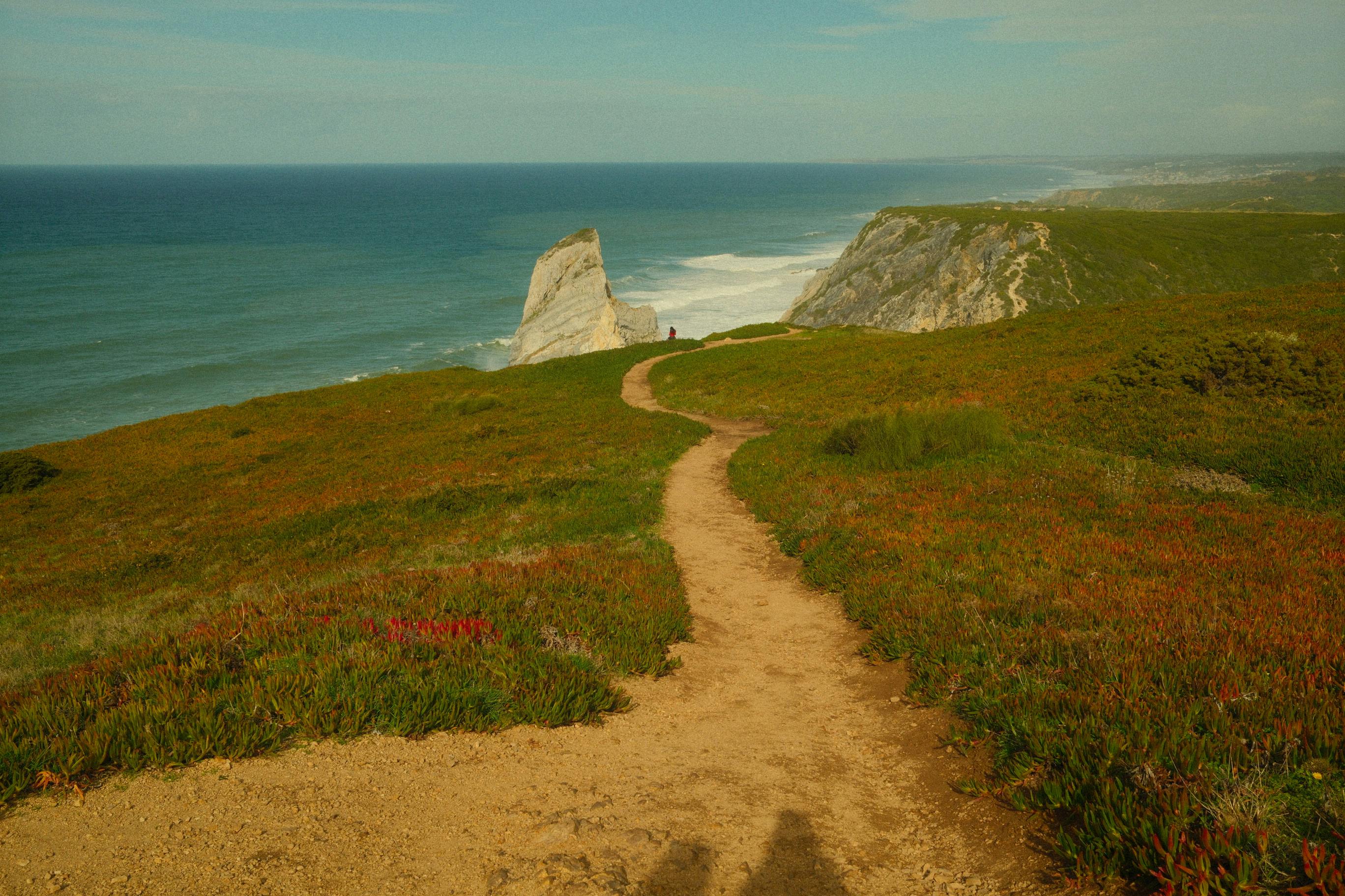 Dramatic coastal landscape with ocean views and lush path in Colares, Portugal.