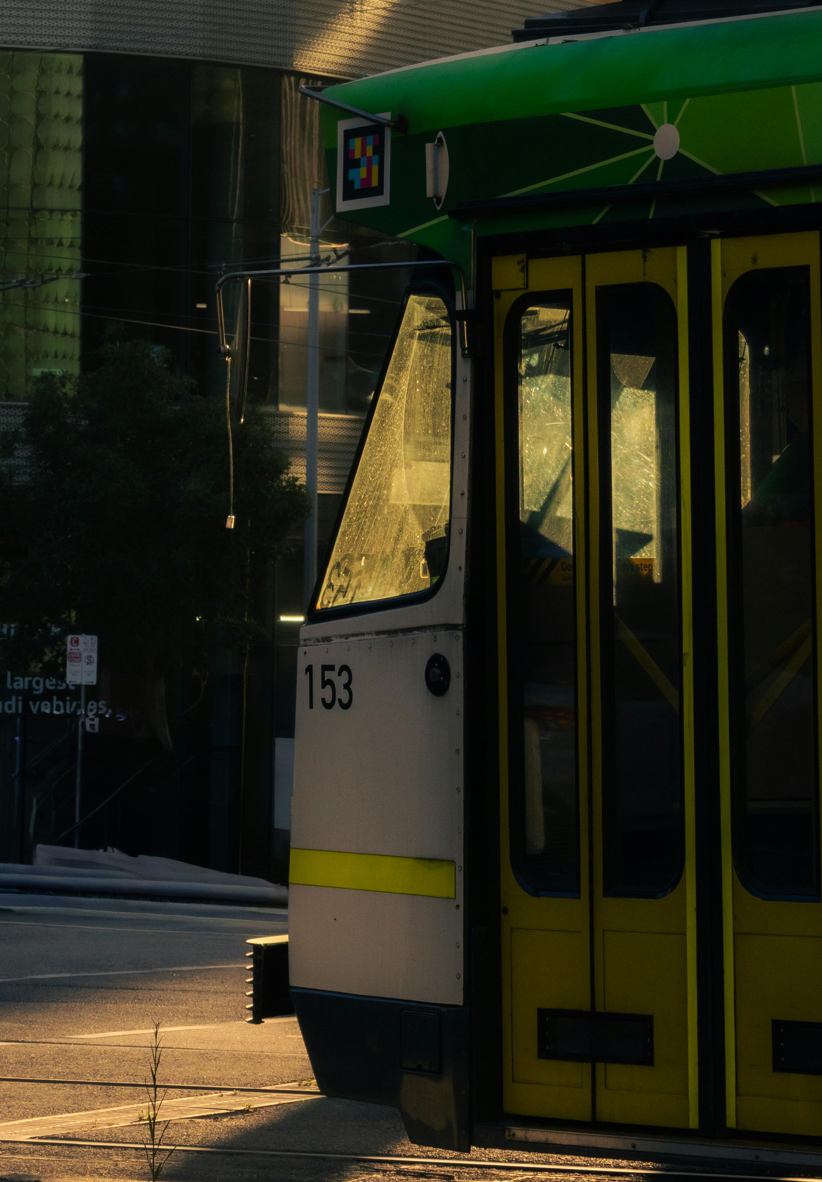 Gratis Primo piano di un tram verde e giallo al tramonto in città, che mostra il trasporto urbano. Foto a disposizione