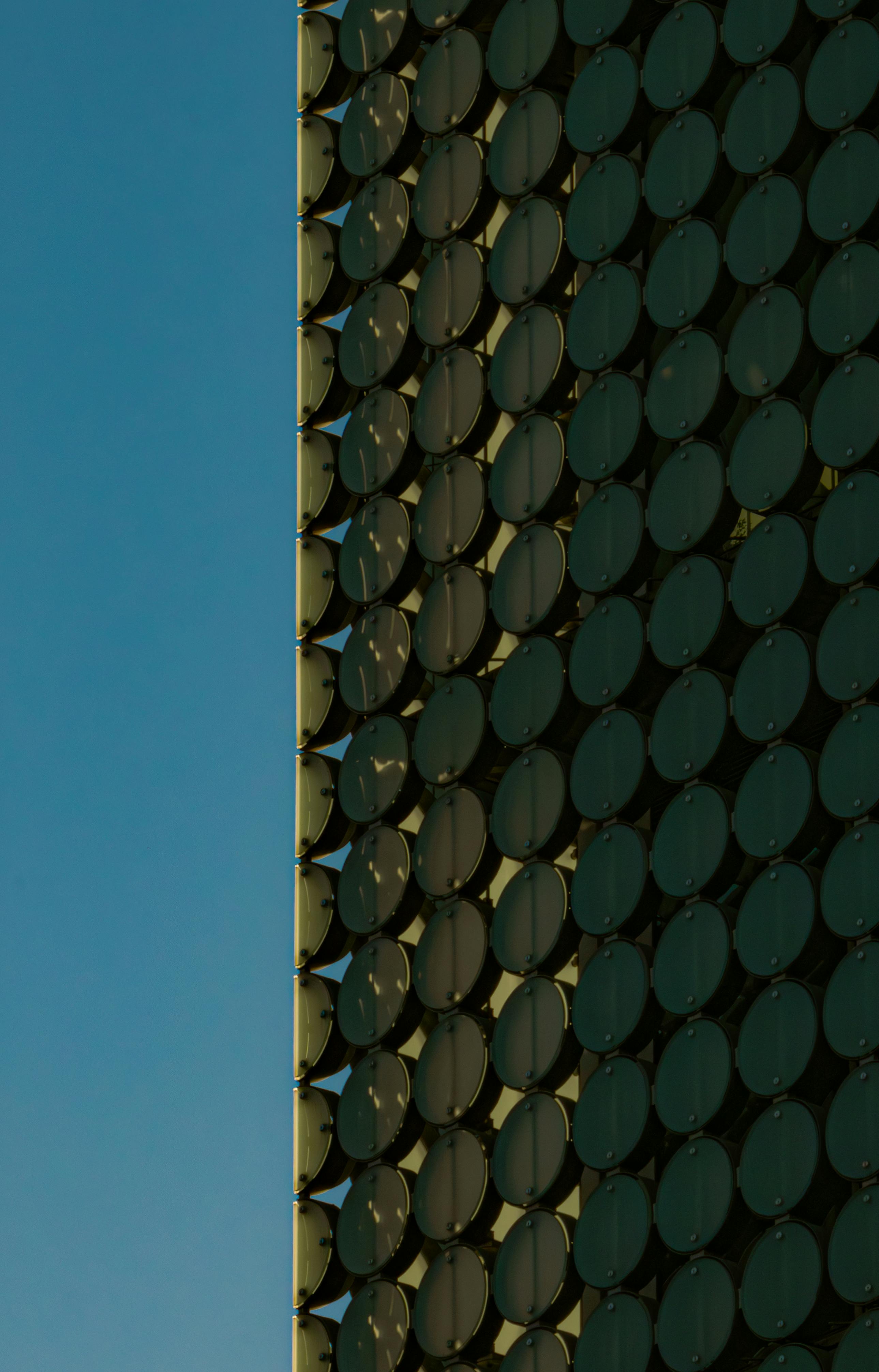 grátis Fachada singular do edifício com motivos circulares contra um céu azul límpido, exibindo arquitetura moderna. Foto profissional