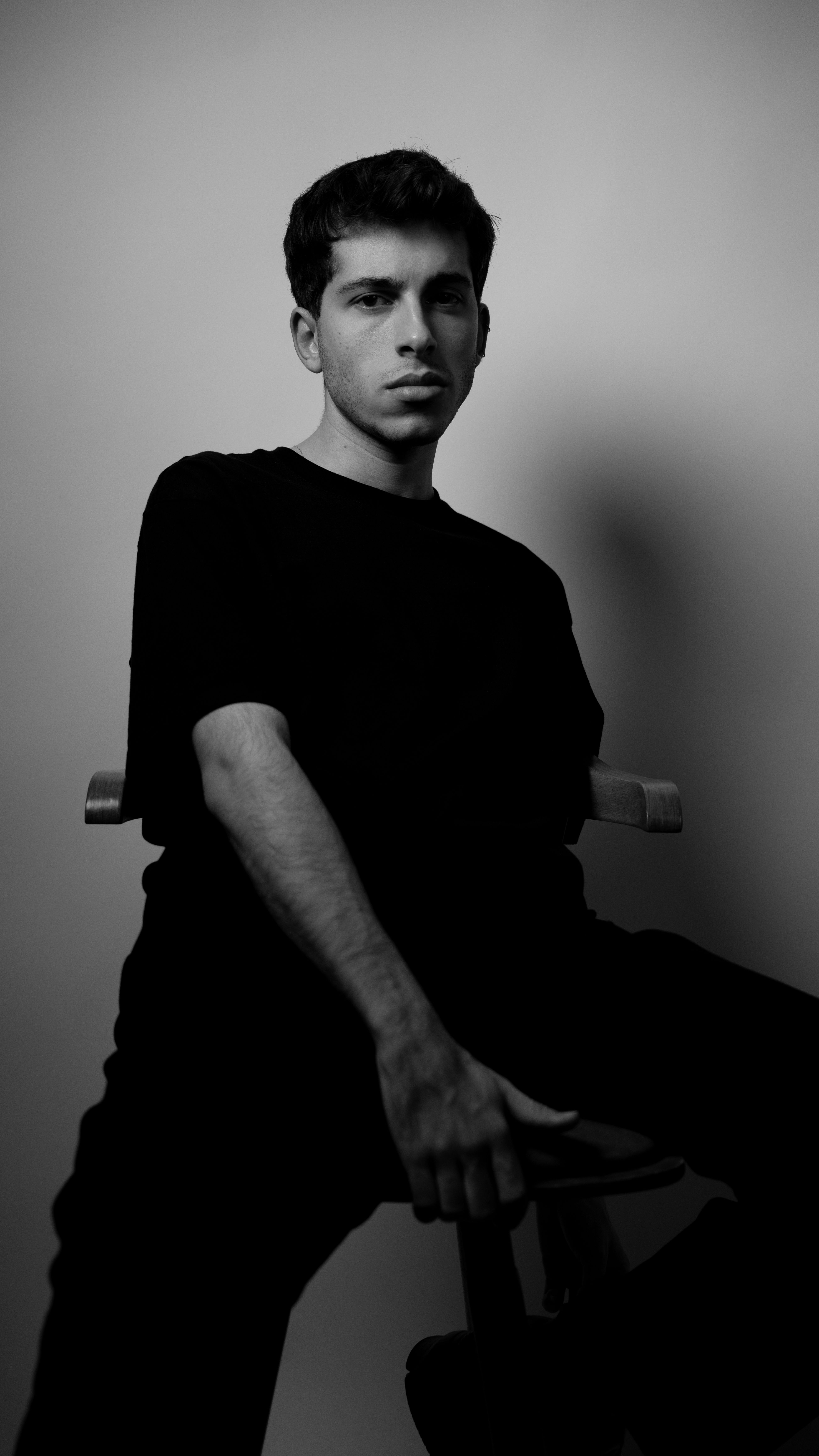 Striking black and white portrait of a male seated in a photo studio, exuding elegance and depth.