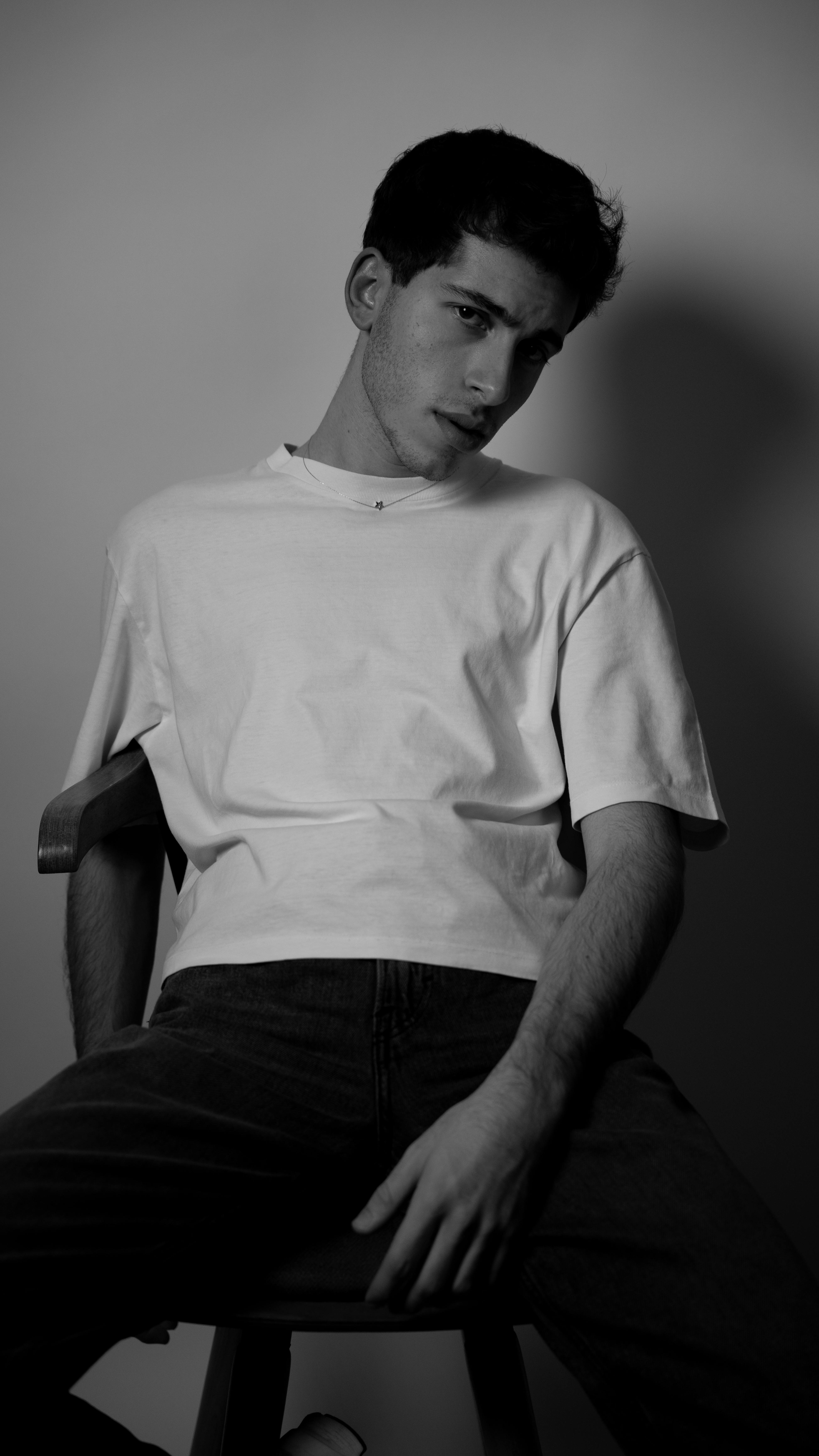 Artistic black and white portrait of a young man wearing a t-shirt in a studio.