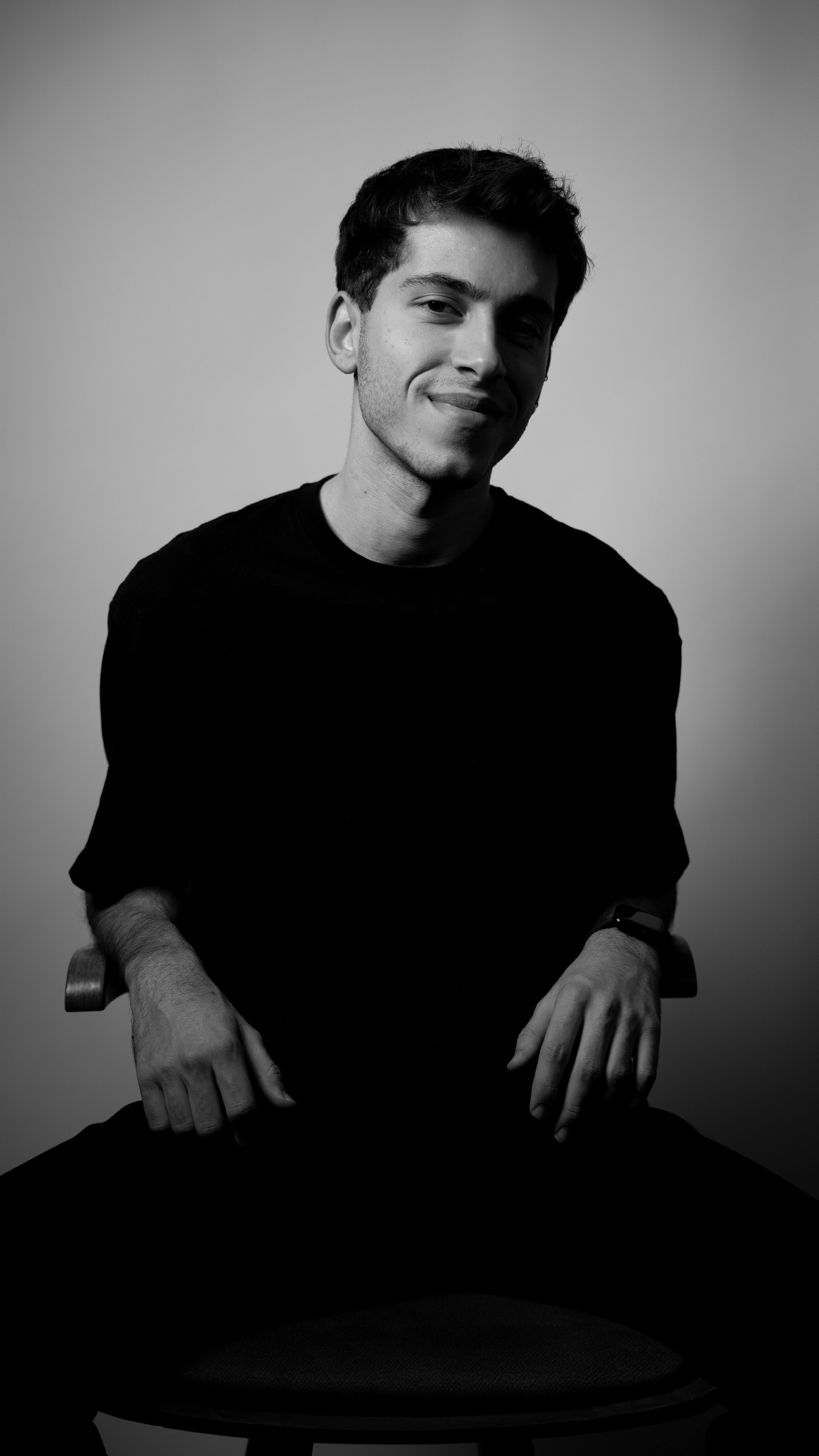 Gratis Ritratto artistico in bianco e nero di un giovane uomo seduto in un interno. Foto a disposizione